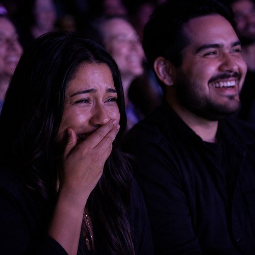 A couple laughing side by side in the crowd