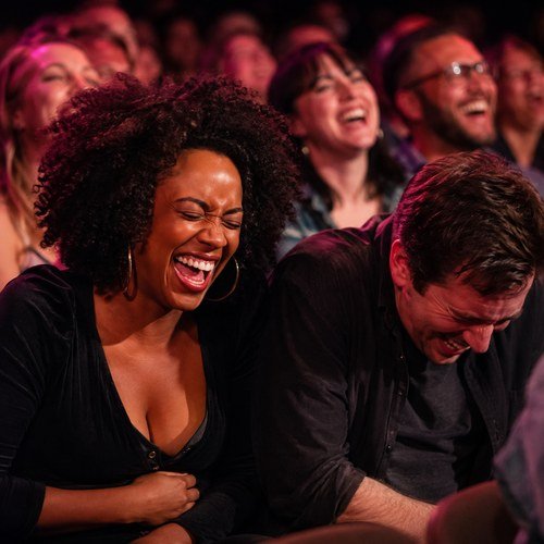 Two audience members laughing with their heads back